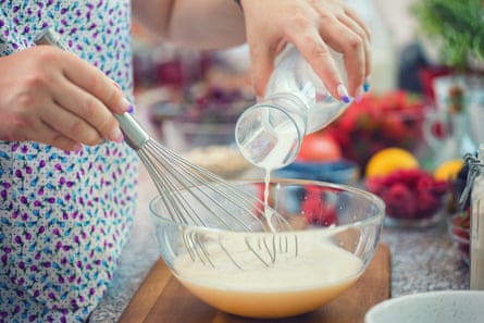 Young woman making pancakes at home, she mixing eggs,batter and milk for pancakes