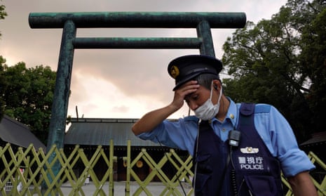 A policeman wipes sweat from his forehead while on duty in the summer heat in front of a Torii gate at the Yasukuni Shrine in Tokyo, Japan, in August.