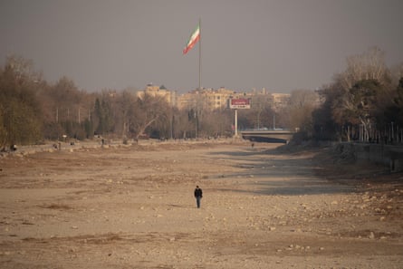 A man walks in a wide expanse of dry soil