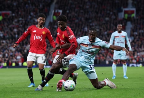 Kobbie Mainoo of Manchester United (centre left) is tackled by Michael Kayode of Brentford.