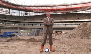 Arsène Wenger stands on the centre spot of the Emirates Stadium during construction in 2005. He was fundamental to the building of the modern, lucrative new ground.