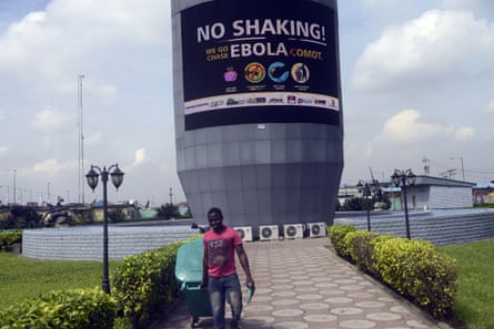 A gardener stands in front of a large electronic sign.