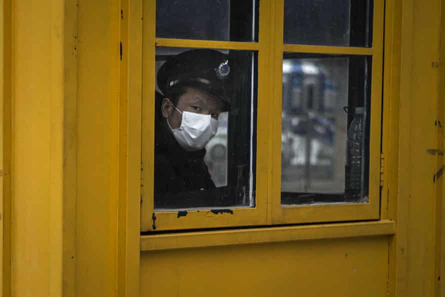 A security guard looks out of the window of a sentry box in Wuhan.