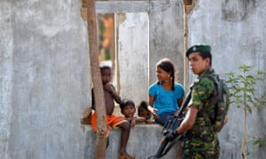 Sri Lankan children look on as a soldier stands guard.