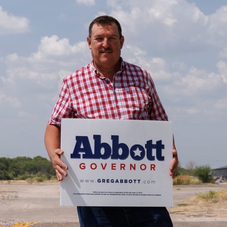 A man holds a Greg Abbott campaign sign.