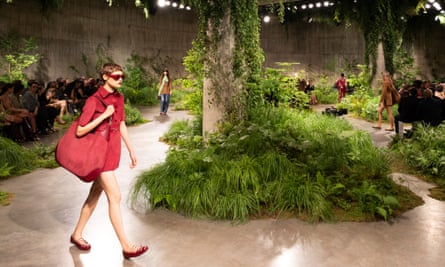A model wears a short cherry-red outfit with matching bag and sunglasses