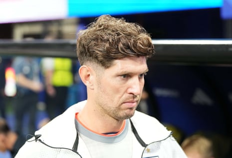 A headshot of John Stones looking down and to the right