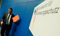 Thomas Haldenwang leaves a press conference in Berlin, January 2019: he is seen holding an orange file and standing against a blue background and a sign for the Federal Office for the Protection of the Constitution