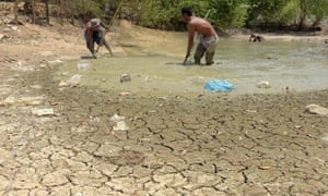 Cambodian men use a net to catch fish in a nearly dried pond at a village in Kandal province.