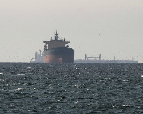 A large cargo ship dominates the foreground with another vessel visible behind it on choppy open water