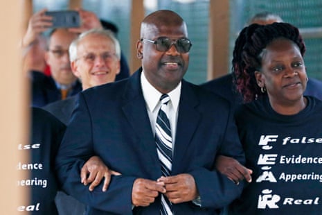 Curtis Flowers, smiling in sunglasses and a suit, walks arm-in-arm with his sister through a crowd outdoors