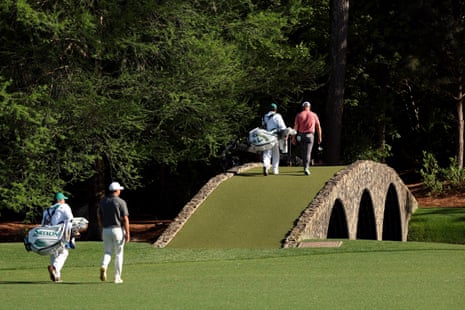 Jon Rahm of Spain and his caddie Adam Hayes cross the Hogan Bridge on the 12th hole as Brooks Koepka of the United States and his caddie Ricky Elliott follow.