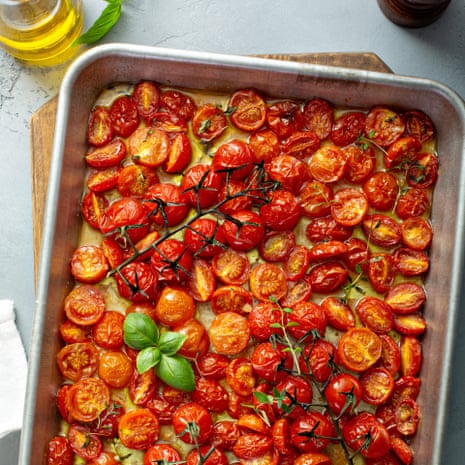 Cherry tomatoes can be baked just by leaving them in the cooling oven after the main dish has been removed. Cherry tomatoes roasted with garlic and spices on a baking tray,