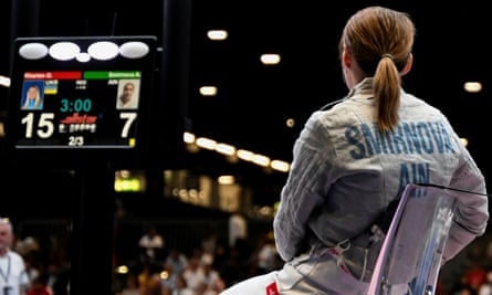 Anna Smirnova sitting on a chair, turned away from the camera, with her name visible on the back of her fencing uniform
