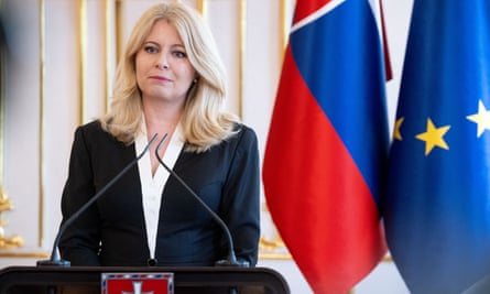 Zuzana Čaputová in front of a mic with flags behind her