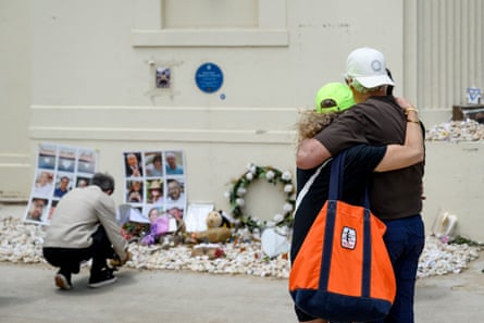 People comfort each other while looking at tributes to the victims of the Hanukah massacre.