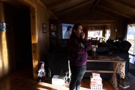 A woman in a purple sweatshirt stands inside her living room