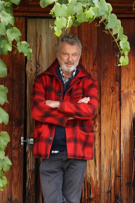 Sam Neill leaning against a wooden fence