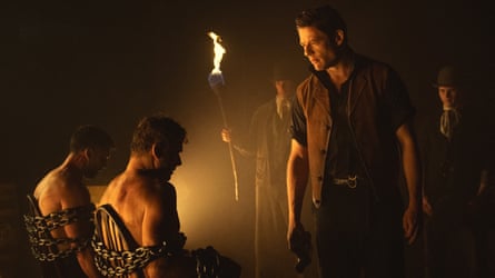 Still from the series shows James Norton staring at two naked men tied to a chair