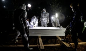 Gravediggers moving a coffin during a funeral for a victim of Covid-19 at a cemetery in Bogor, Indonesia