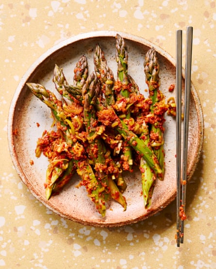 A round plate of asparagus kimchi, with chopsticks at the side.