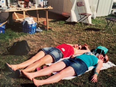 Two young women wearing denim shorts lying on a towel on the grass outside a camping area