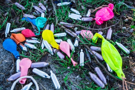 Laughing gas canisters and balloons discarded in a grass field