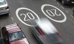 20 mph speed limit markings on a road with speeding cars.