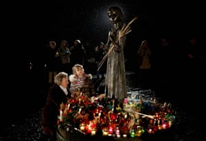 A woman with a girl places a candle at a monument in Kyiv, Ukraine, to victims of the Holodomor during a commemoration ceremony of the famine of 1932-33