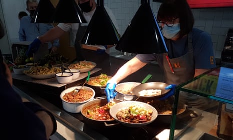 People helping themselves to food in a cafeteria.
