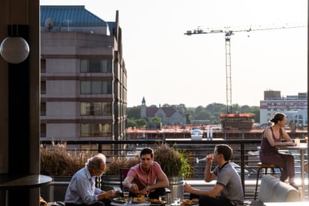 People having drinks on a rooftop with a crane in the background