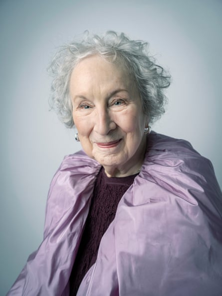 Margaret Atwood pictured from the waist up wearing a deep-purple fringe-T-shirt beneath a lilac cape-like shawl, which is draped around her