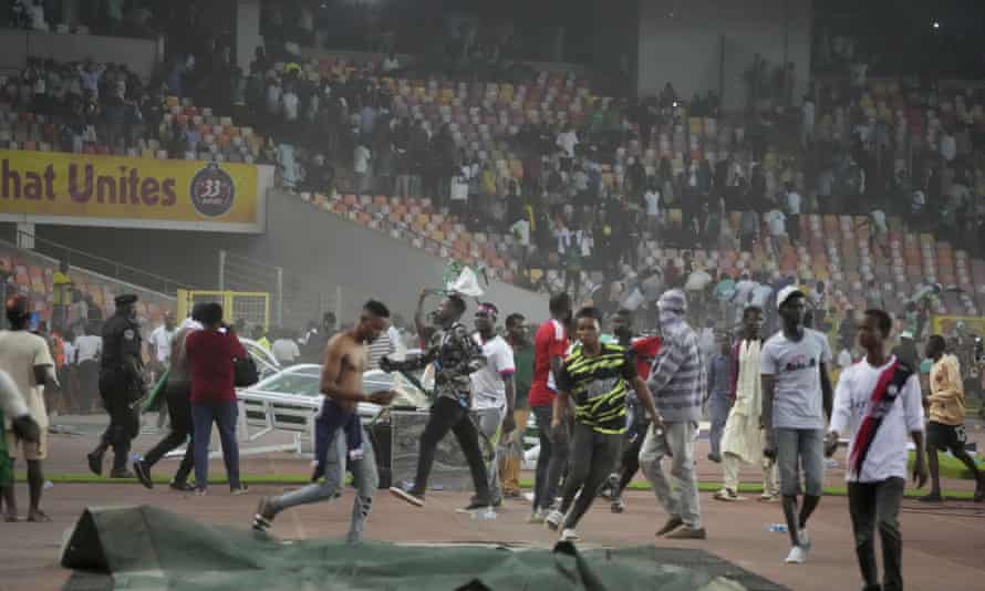 Police fire tear gas to try to remove Nigerian spectators from the pitch after Ghana qualified at Nigeria’s expense on away goals.