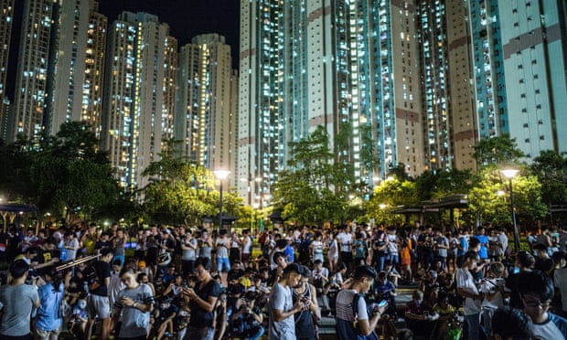 Pokémon Go players gather under night lights against a backdrop of skyscrapers at the game's Hong Kong launch in 2016.