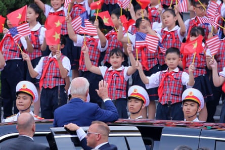 Joe Biden waves to children waving US and Vietnamese flags after a military welcome ceremony at the presidential palace in Hanoi, Vietnam, on 10 September 2023.