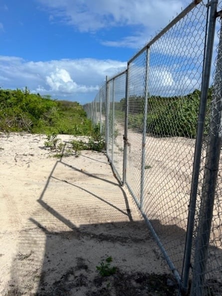 A metal fence across a sandy road