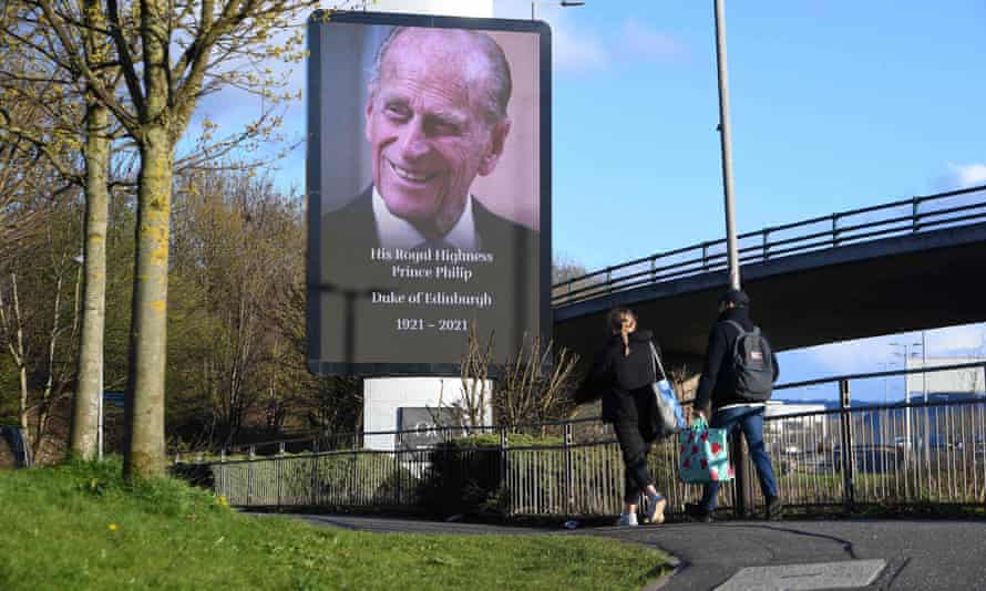 People walk past a billboard paying tribute to Prince Philip in Glasgow