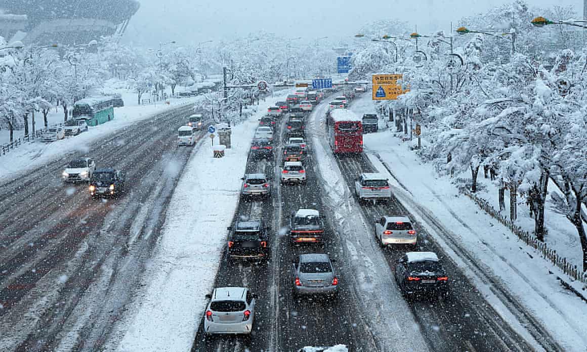 Cars move slowly on a road heavy snowfall.