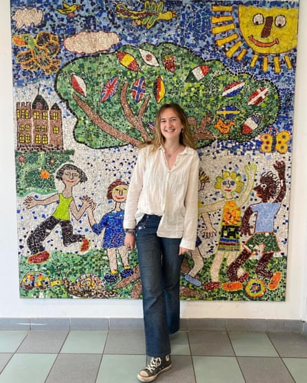 Lia Middleton, in a white shirt, jeans and Converse stands in front of a mosaic-like child’s picture