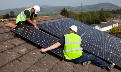 Workers install solar panels on a roof in Wales