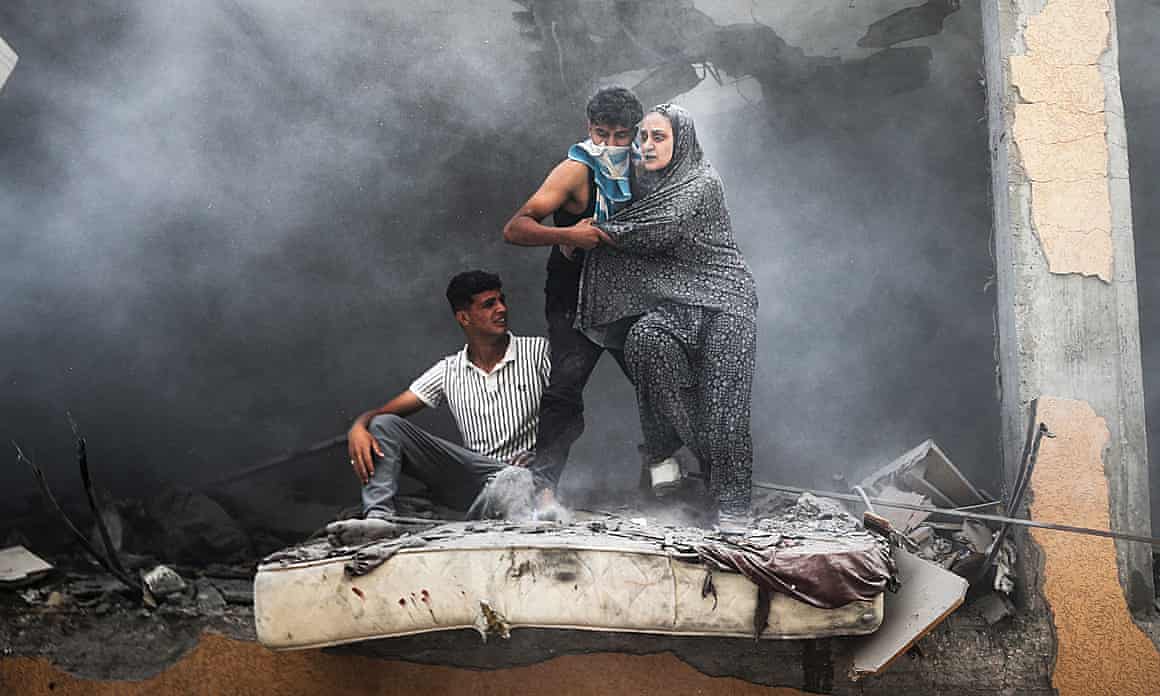 People covered in dust, emerging from the rubble as smoke billows around them