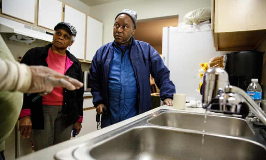 A handyman explains the new water filter to Mary Stewart and Terrence Tyler at their residence in Flint, Michigan.