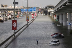 A person stands surrounded by flood water in Dubai