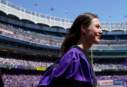 Sanna Marin wears purple academic regalia as she walks to a stage.