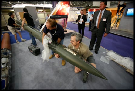 Four men hold a missile as they lift it to put on show at the stand in the exhibition centre