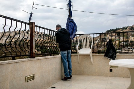 A man stands looking over railings from a roof terrace