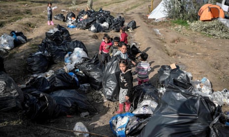 Children help clean the makeshift migrant camp on the Greek island of Chios on 11 December