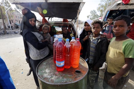 Yemenis stand near bottles full of fuel displayed for sale at a black market amid an acute shortage of fuel in Sana’a, Yemen