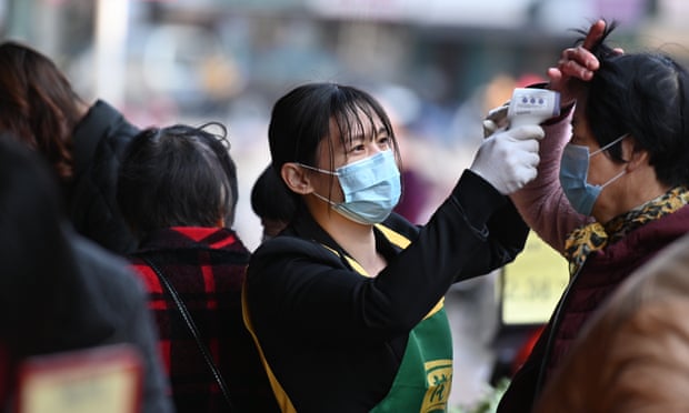 A person wearing a face mask is checking temperatures in Nanan Fujian, China, as the death toll from coronavirus passes 420. 