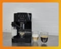 A De'Longhi Magnifica Start coffee machine dispenses coffee beside milk and two filled glasses.